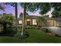 Charming single-story home featuring lush landscaping, a two-car garage, and a covered front entry at 1118 Captains Way, Tarpon Springs, FL 34689