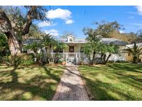 Charming single-story home with a brick walkway, palm trees, and a welcoming front porch at 13015 Elm St, Odessa, FL 33556