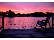 Beautiful pink sunset over a lake with a rocking chair sitting on the edge of a wooden dock at 3629 Lake Breeze Dr, Land O Lakes, FL 34639