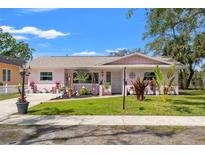 Charming pink single-story home with a well-manicured lawn and sidewalk at 408 Pineapple St, Tarpon Springs, FL 34689