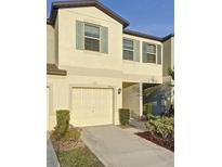 Two-story townhome featuring a one-car garage, and neutral paint with decorative blue shutters at 4461 Globe Thistle Dr, Tampa, FL 33619