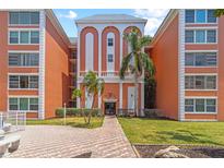 Exterior view of condo building featuring a grand entrance, well-manicured lawn, and tropical landscaping at 6800 20Th N Ave # 307, St Petersburg, FL 33710