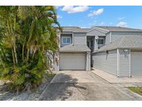 Inviting two-story townhouse featuring an attached garage, palm trees, and neutral siding at 9727 Tiffany Oaks Ln, Tampa, FL 33612