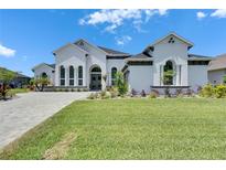 Stunning white home featuring lush landscaping and a paved driveway on a sunny day at 13539 Carryback Dr, Dade City, FL 33525