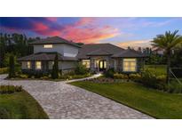 Stunning exterior showcasing stone accents, tile roof, paver driveway, and professional landscaping under a vibrant sunset sky at 17305 Ballmont Park Dr, Odessa, FL 33556