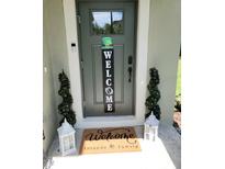 Charming front door with welcome mat, festive decor, and potted spiral topiary trees at 5131 Forum Blvd, Holiday, FL 34690