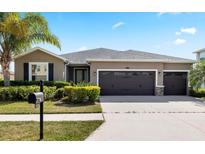 Charming single-story home with a three-car garage, mature landscaping, and a well-manicured lawn at 5453 Suncatcher Dr, Wesley Chapel, FL 33545