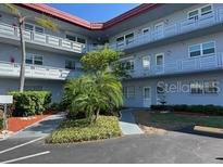 Three story condo building featuring a well maintained lawn with mature palm trees and tropical landscaping at 5660 80Th N St # A102, St Petersburg, FL 33709