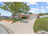 Charming single-story home with a well-manicured lawn, mature tree, and long driveway at 10448 Hetrick W Cir, Largo, FL 33774