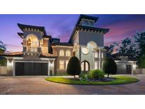 A luxurious home featuring a tower entry, arched windows, a balcony, multi-car garage, and an inviting driveway at 1600 Magnolia Rd, Belleair, FL 33756