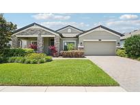 Beautiful front yard with lush green grass, colorful landscaping, and charming exterior of the home at 1741 Cherry Walk Rd, Lutz, FL 33558