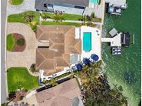 An aerial view showcasing a waterfront property with a private pool, boat dock, and meticulously manicured lawns at 2233 Donato Dr, Belleair Beach, FL 33786