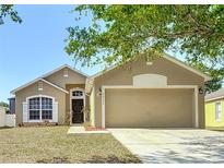 Charming single-story home with a two-car garage, manicured lawn, and inviting curb appeal on a sunny day at 36144 Markree Castle Ave, Dade City, FL 33525