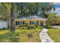 Charming yellow home with dark shutters, lovely landscaping, and a welcoming walkway leading to the front door at 4124 W San Juan St, Tampa, FL 33629