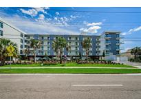Modern condo building featuring well-kept landscaping, palm trees, and stylish architectural design at 415 Island Way # 511, Clearwater Beach, FL 33767