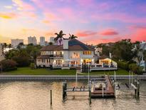 A waterfront home is situated with a private dock and expansive windows to enjoy sunsets from the outdoor seating area at 429 St Andrews Dr, Belleair, FL 33756