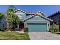 Charming two-story home with a well-manicured lawn, colorful plants, and a bright blue two-car garage at 7513 S Sparkman St, Tampa, FL 33616