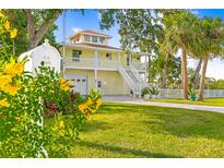 Charming yellow two-story home with white stairs, railings, and lush landscaping at 8717 Betty St, Port Richey, FL 34668