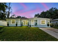 Charming single-story home with well-maintained lawn and landscaping, set against a lovely pink and blue twilight sky at 6914 N Ola Ave, Tampa, FL 33604