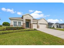 Charming single-story home with a manicured lawn, stone accents, and a three-car garage at 13953 Thoroughbred Dr, Dade City, FL 33525