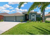 Charming single-story home featuring a well-manicured lawn, arched entryway, and a spacious three car garage at 2321 Wood Pointe Dr, Holiday, FL 34691