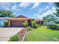 Charming single-story home with a well-maintained lawn, mature landscaping, and a two-car garage at 2597 Bramblewood E Dr, Clearwater, FL 33763