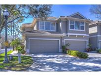 Two-story townhome featuring a two-car garage, neutral paint, and tiled roof and manicured landscaping at 3292 Covered Bridge E Dr, Dunedin, FL 34698