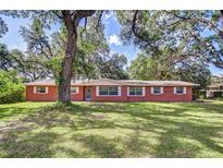 Charming single-story brick home featuring a lush green lawn and mature trees at 37348 Tucker Rd, Zephyrhills, FL 33541
