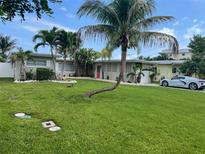 Beautiful single-story home with a well-maintained lawn, lush landscaping and a striking red front door at 419 12Th Ave, Indian Rocks Beach, FL 33785