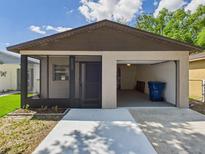 Detached garage featuring an open bay door, screened-in porch, fresh landscaping and ample driveway space at 4937 Steel Dust Ln, Lutz, FL 33559