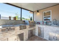 An outdoor kitchen with stainless steel appliances, granite countertops, and a built-in sink, perfect for entertaining at 6328 S Harold Ave, Tampa, FL 33616