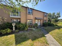 Charming two-story condo with a welcoming walkway and a well-maintained lawn and tropical landscaping at 1883 Clearbrooke Dr, Clearwater, FL 33760