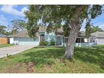 Charming home with a well-maintained lawn and mature trees providing shade, featuring a light blue exterior at 3093 Woodpine Cir, Sarasota, FL 34231