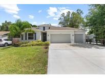 Charming single story home featuring a well-manicured lawn, a two car garage, and tropical landscaping at 3605 W Paxton Ave, Tampa, FL 33611