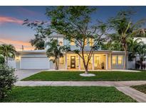 Beautiful two-story home featuring a well-manicured lawn, covered porch, and inviting curb appeal at dusk at 3711 W Barcelona St, Tampa, FL 33629