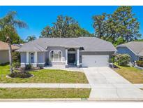 Beautiful single-story home featuring a well-manicured lawn, gray exterior paint and two-car garage on a sunny day at 4951 Musselshell Dr, New Port Richey, FL 34655