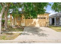 Exterior view of the house featuring a 2 car garage with exterior lights, driveway, and lush front yard with mature trees at 8420 Deer Chase Dr, Riverview, FL 33578