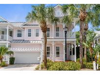 Charming two-story home featuring a double porch, painted in a light pink, with palm trees in the front yard at 916 Hemingway Cir, Tampa, FL 33602