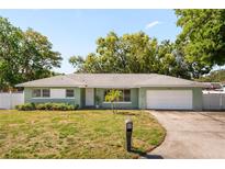 Charming single-story home with a well-manicured lawn, a mature palm tree and attached two-car garage at 1809 Stancel Dr, Clearwater, FL 33764