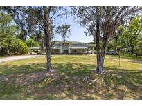 Inviting two-story home with lush front lawn and covered parking, framed by mature trees and ample space at 592 Ken Hubbard Rd, Terra Ceia, FL 34250