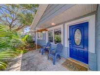 Charming front porch with blue chairs, patterned tile, and a vibrant blue door at 135 Coral Dr, Safety Harbor, FL 34695