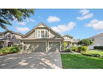 Charming two-story home with a well-maintained lawn and a three-car garage on a sunny day at 17124 Falconridge Rd, Lithia, FL 33547