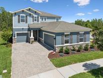 Beautiful two-story home featuring a manicured lawn and a paver driveway on a sunny day at 18219 Ramble On Way, Land O Lakes, FL 34638