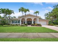 Charming home with a well-manicured lawn and palm trees, offering a welcoming curb appeal and architectural detail at 206 Corbett St, Belleair, FL 33756