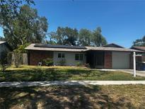 Charming single-story home with a well-manicured lawn, solar panels, and brick accents at 2154 Briarway Dr, Clearwater, FL 33763