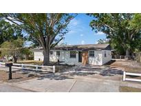 Charming single-story home with a white picket fence and mature trees in a sunny outdoor setting at 324 Country Club Dr, Oldsmar, FL 34677