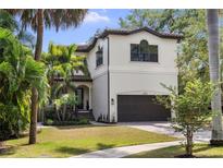 Elegant two-story home featuring a two-car garage, lush landscaping, and a charming front entry with stately columns at 4804 W Beachway Dr, Tampa, FL 33609