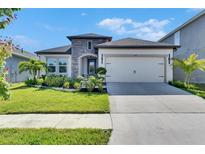 Charming single-story home featuring stone accents, a well-manicured lawn, and a two-car garage at 6252 Hidden Branch Dr, Apollo Beach, FL 33572