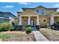 Inviting two-story townhome featuring a covered front porch with stately columns and professionally landscaped front yard at 6918 Frog Pocket Pl, Tampa, FL 33616