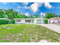 Charming single-story home with a well-maintained lawn, complemented by a light-green garage and front door at 2220 Calexico S Way, St Petersburg, FL 33712
